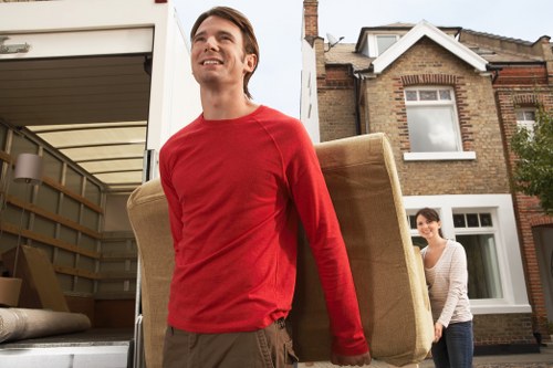 Movers carrying furniture through a stairwell in a local Swiss Cottage property